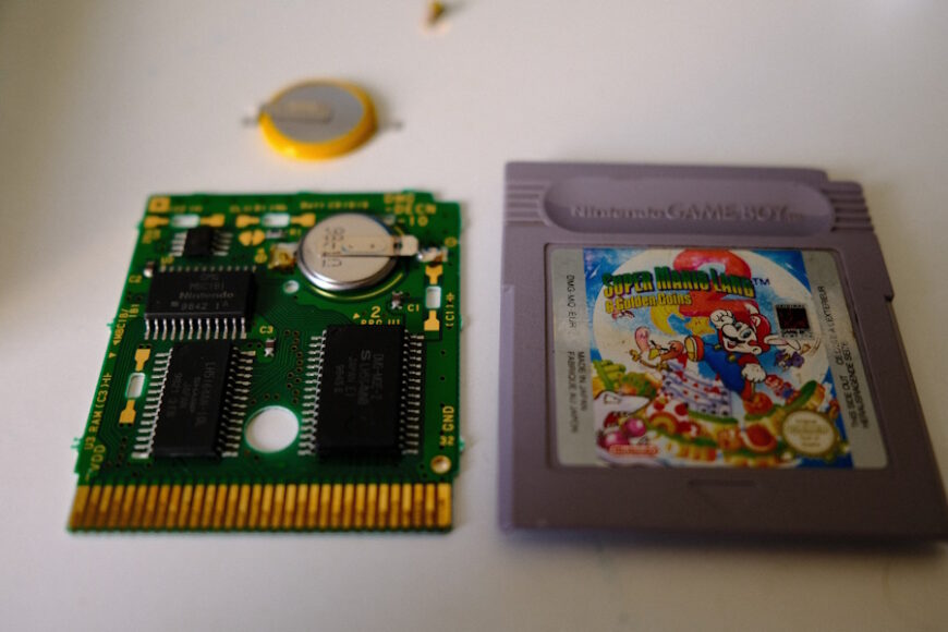 Cartouche Game Boy Super Mario Land 2 : 6 golden coins ouverte avec pile de sauvegarde visible et pile de rechange